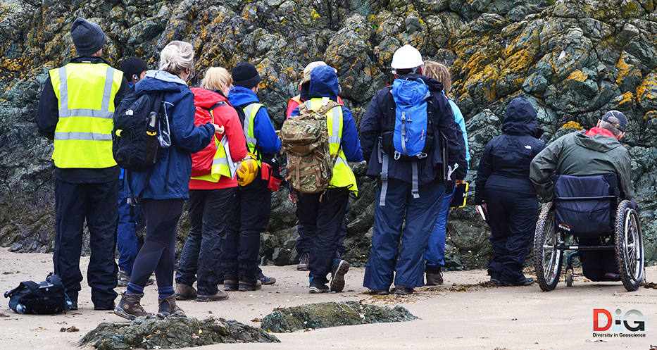 A diverse group of students including a wheelchair user looking at an outcrop of pillow lava in Anglesey, Wales, UK.
